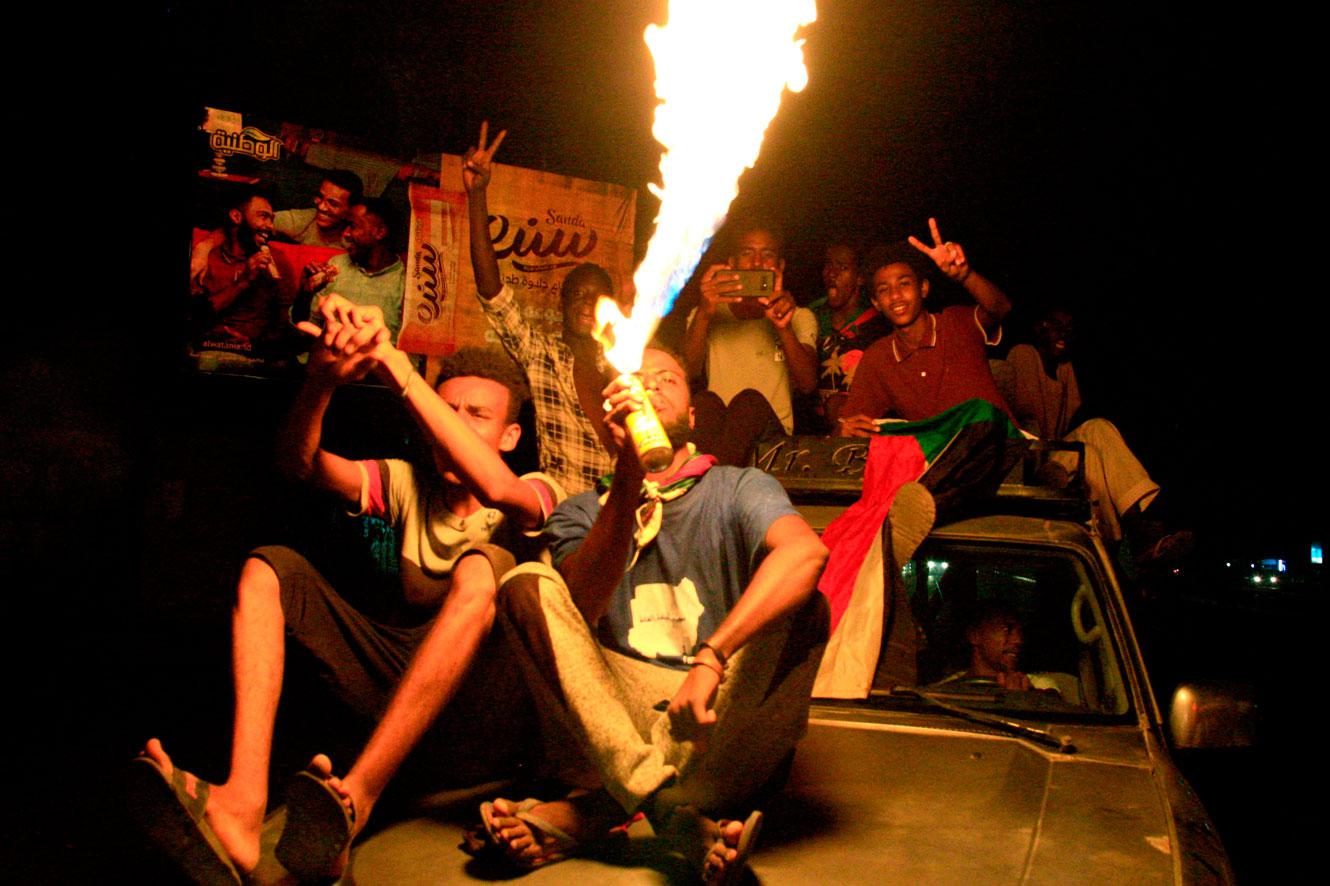 A man sets a gas canister on fire as Sudanese demonstraters celebrate in Khartoum