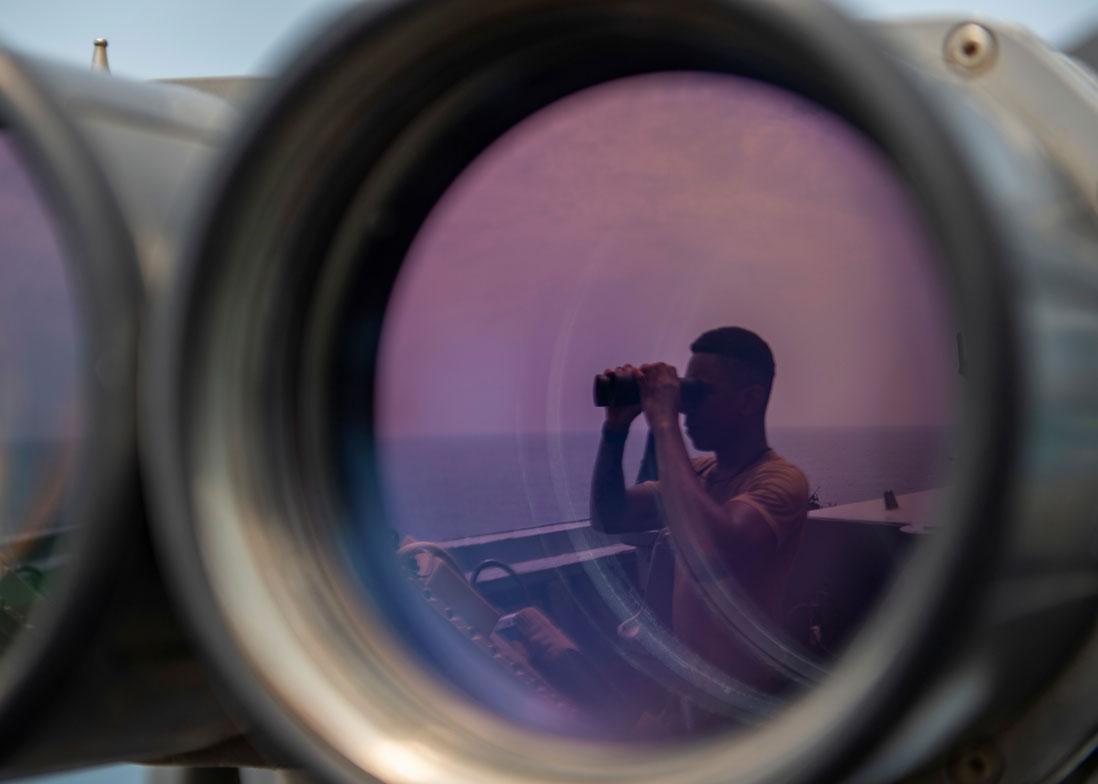 A US sailor uses binoculars to scan the ocean during a bridge watch aboard a US guided-missile destroyer in the Gulf