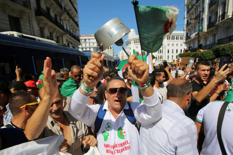 A demonstrator bangs a pot during a protest demanding social and economic reforms as well as the departure of the country’s ruling elite in Algiers