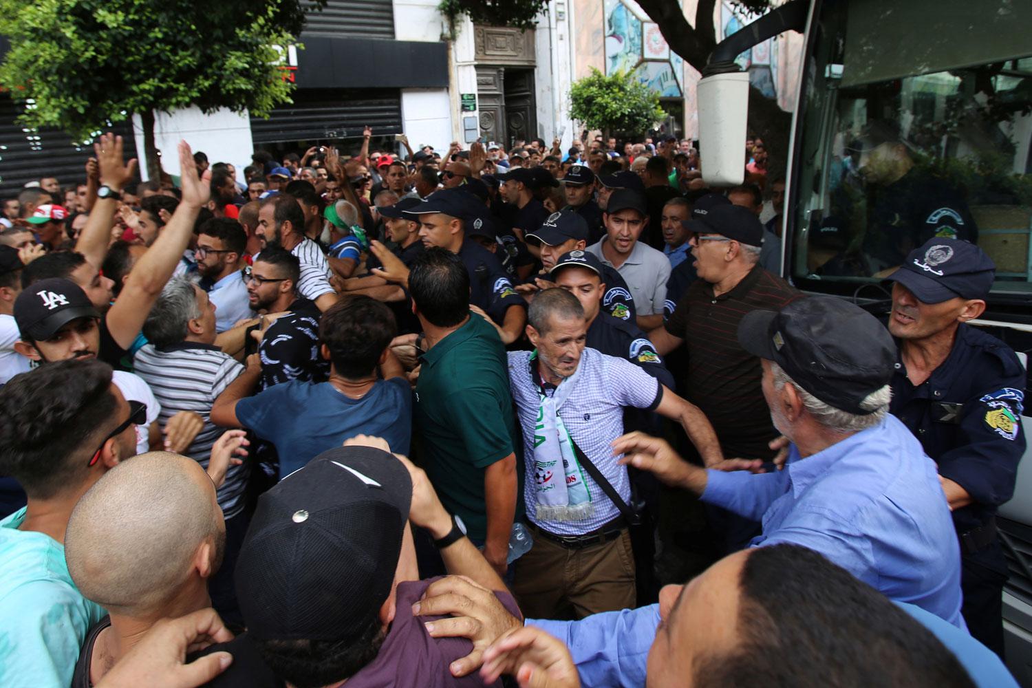 Police officers stand guard as demonstrators try to force their way during a protest
