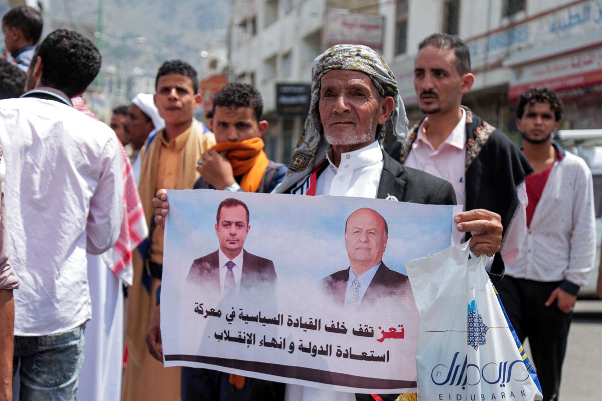 A demonstrator marches with a sign declaring support for Yemen's government
