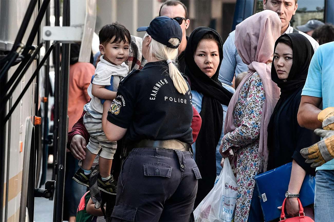 Evicted migrants board buses during a police operation in the center of Athens
