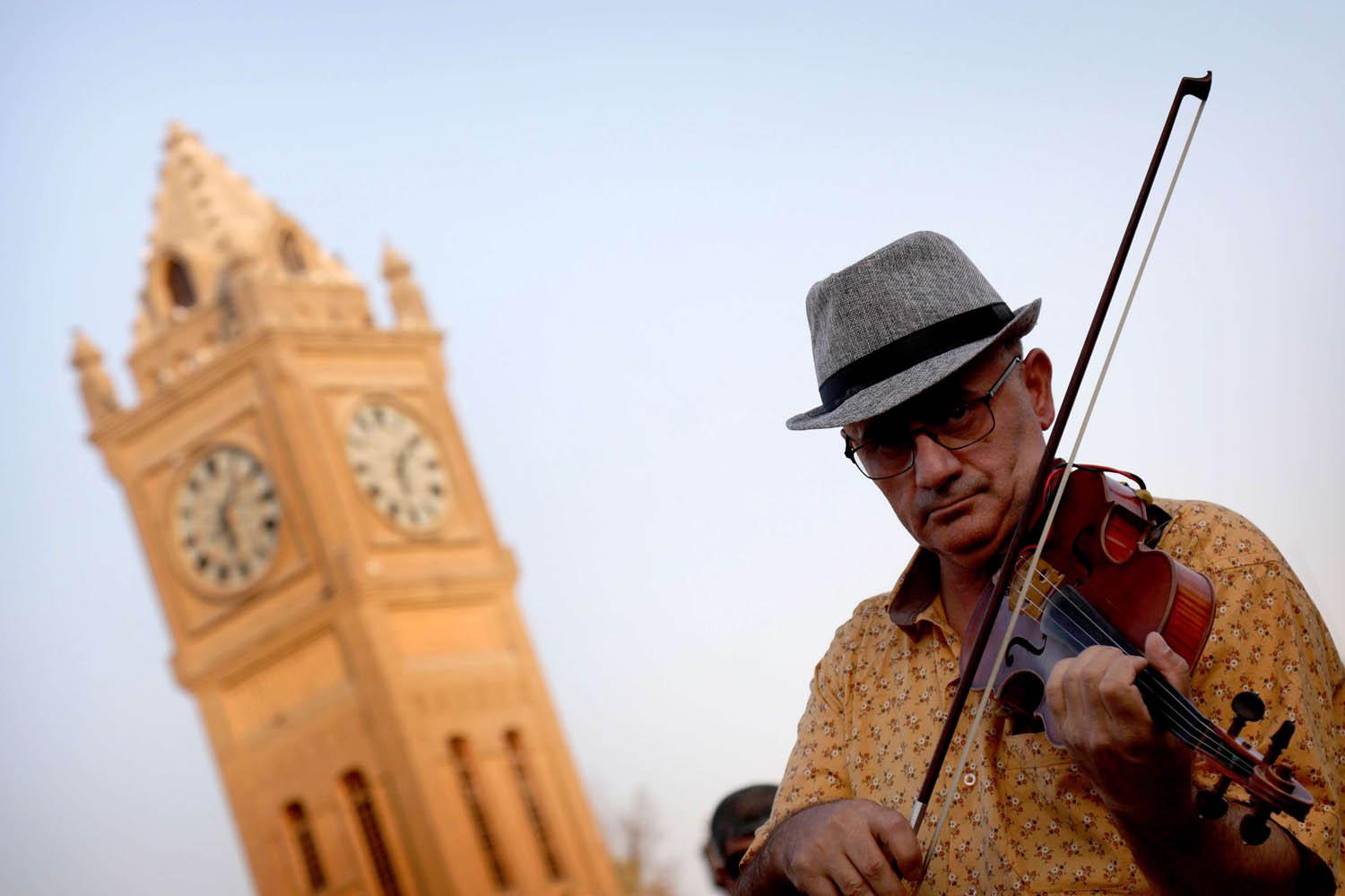 كردي يعزف على الكمان أمام برج قلعة كركوك