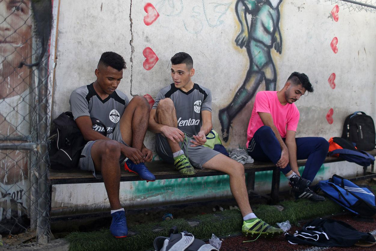 Palestinian players of Gaza soccer club Khadamat Rafah take off their boots after a training session in Rafah