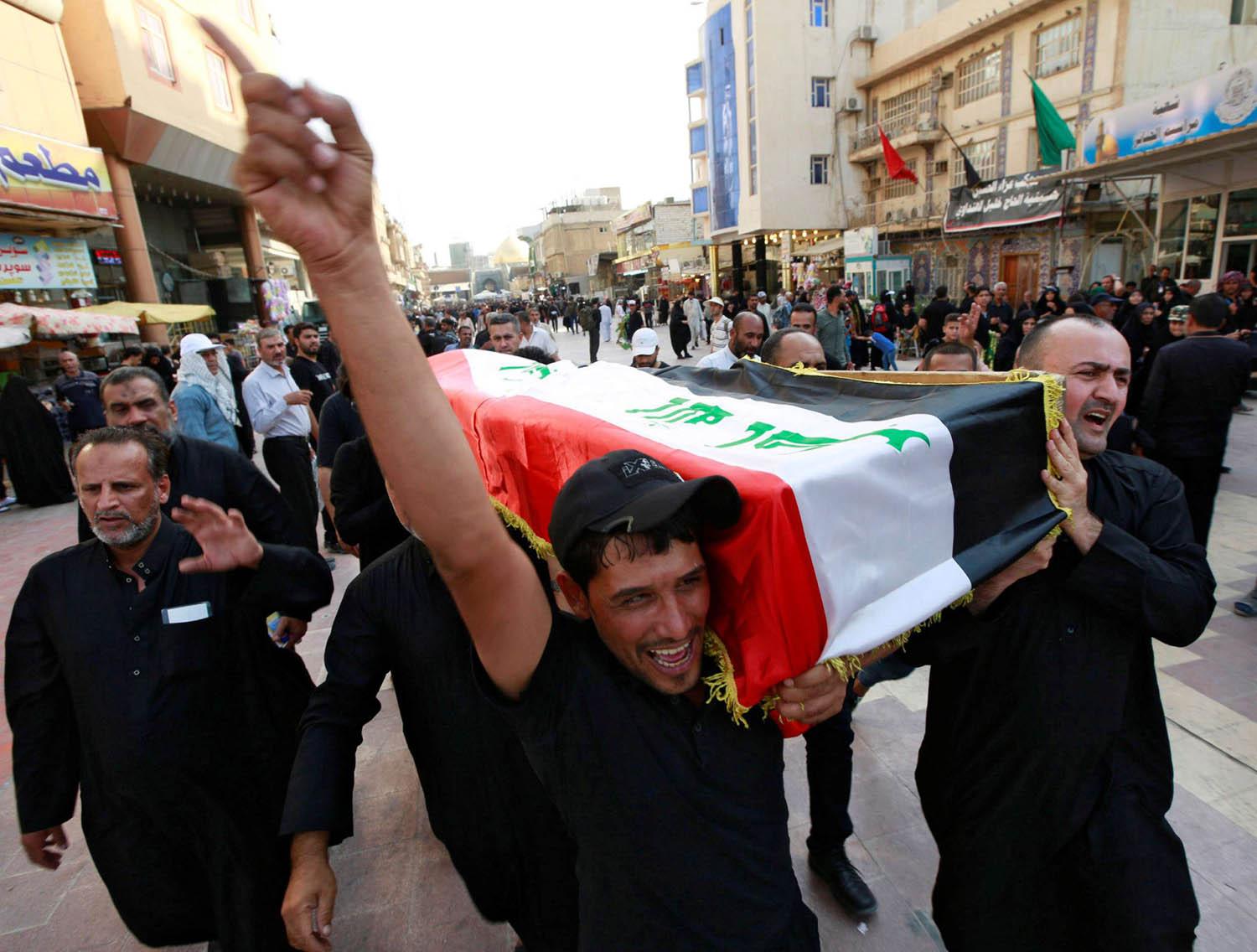 عراقيون يحملون جثمان متظاهر عراقي في النجف قتل على يد قوى الأمن