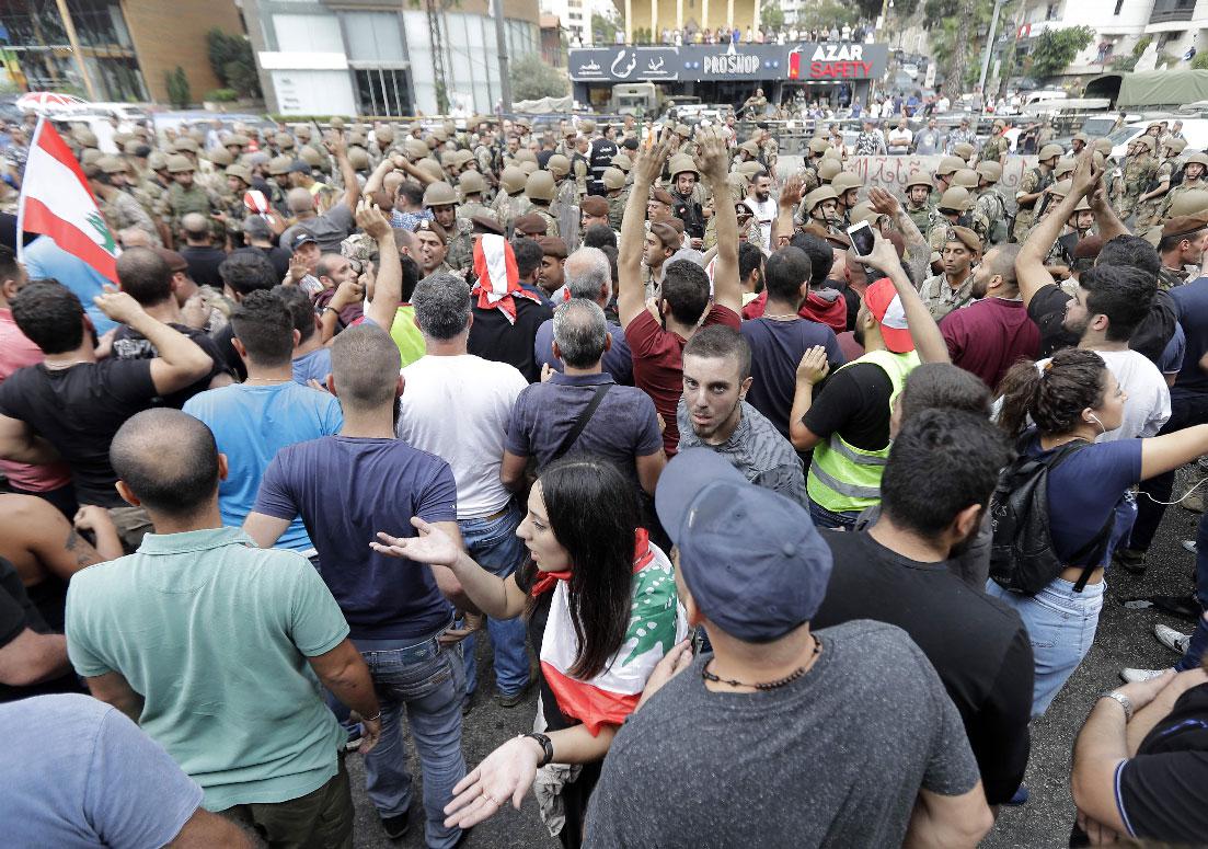 Lebanese protesters facing army soldiers yell slogans in the area of Zouk Mosbeh north of the capital Beirut