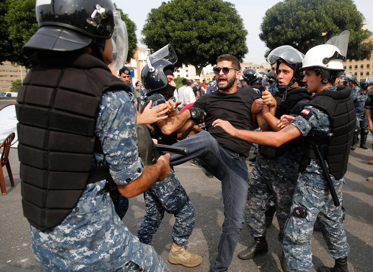 Police remove an anti-government protester blocking a main highway with his body in Beirut