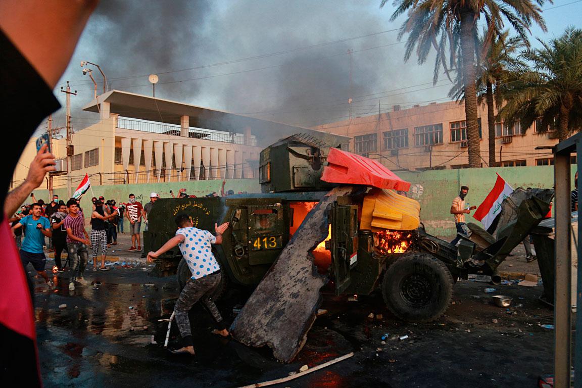 Anti-government protesters burn an armoured vehicle belonging to the Federal Police Rapid Response Forces during a protest in Baghdad