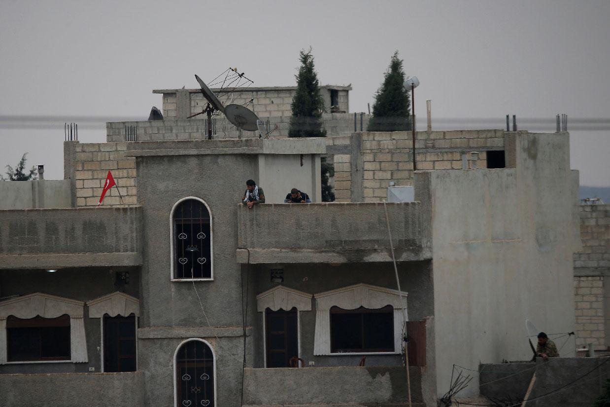 Turkey-backed Syrian rebel fighters stand on a building in the Syrian town of Ras al Ain
