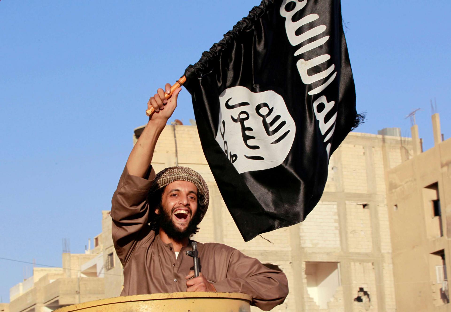 A militant Islamist fighter waving a flag, cheers as he takes part in a military parade along the streets of Syria's northern Raqqa province June 30, 2014