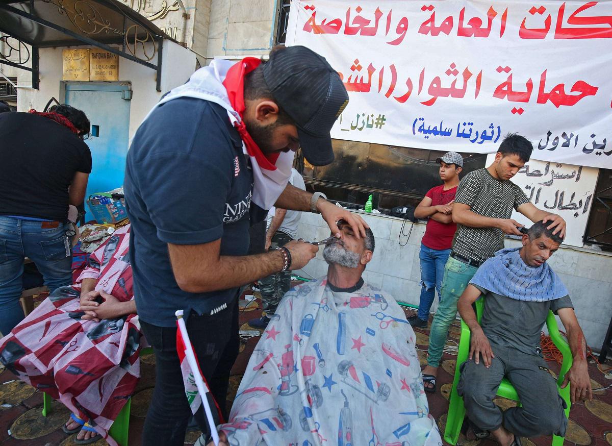 متظاهرون يحصلون حلاقة مجانية في ميدان التحرير ببغداد