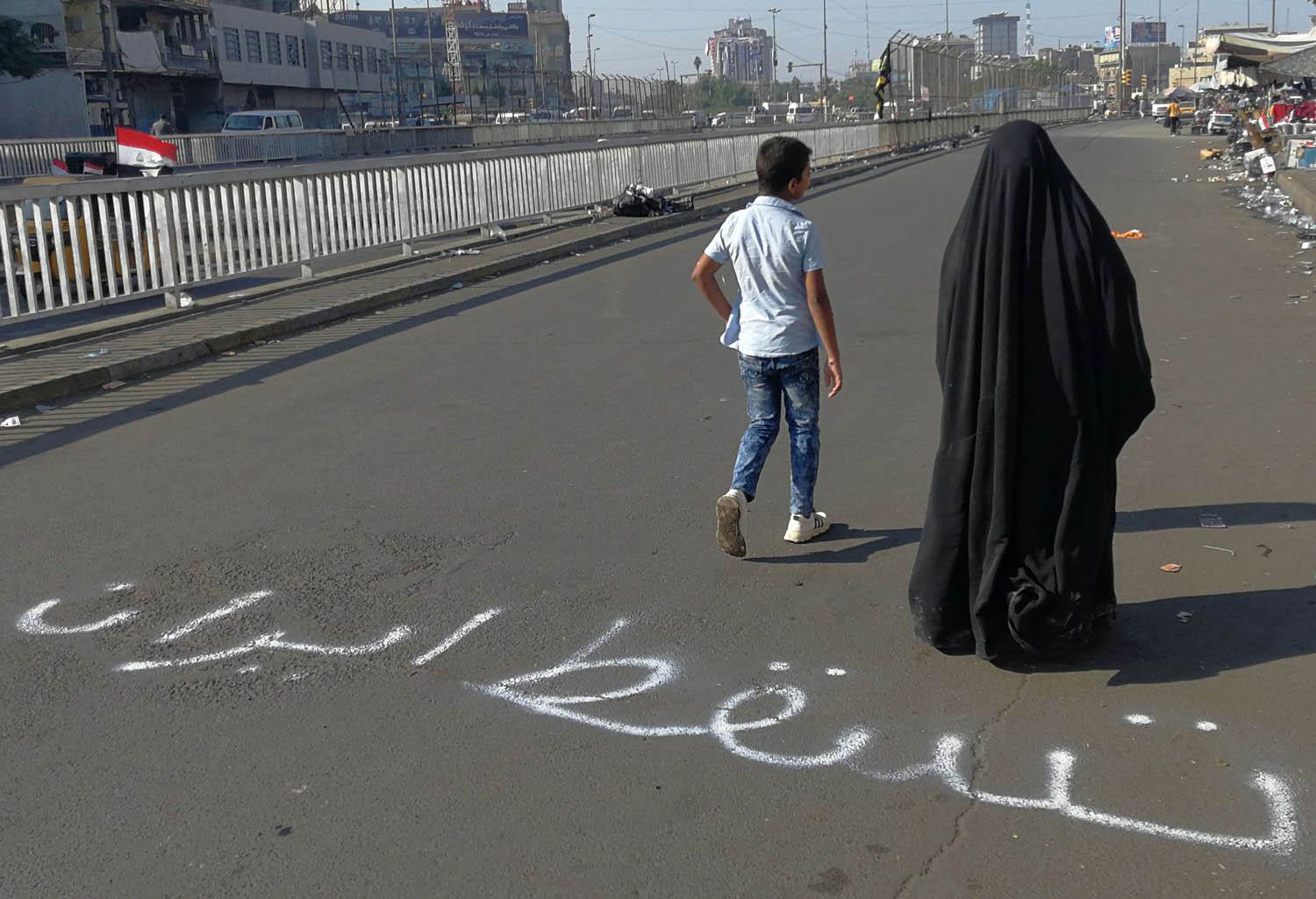 أم عراقية وابنها يمران في منطقة الاعتصامات في بغداد
