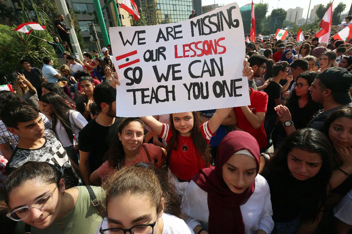 A student carries a banner during ongoing anti-government protests near the Ministry of Education and Higher Education in Beirut