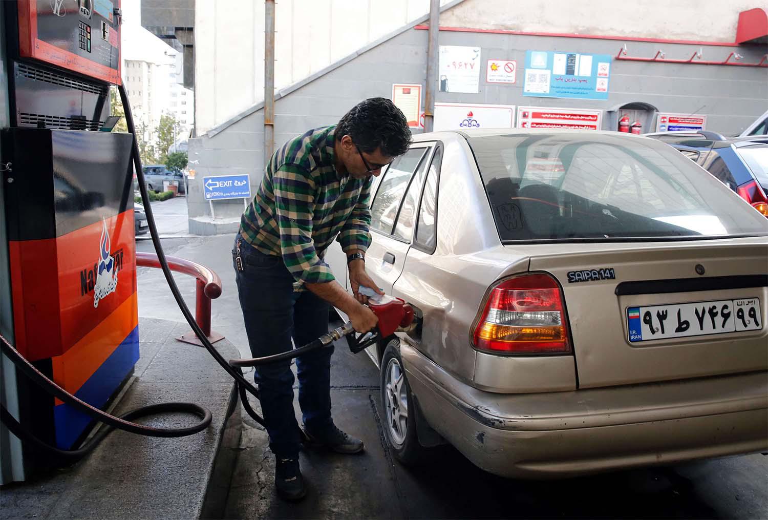 Iranian fills his vehicles at a petrol station in Tehran