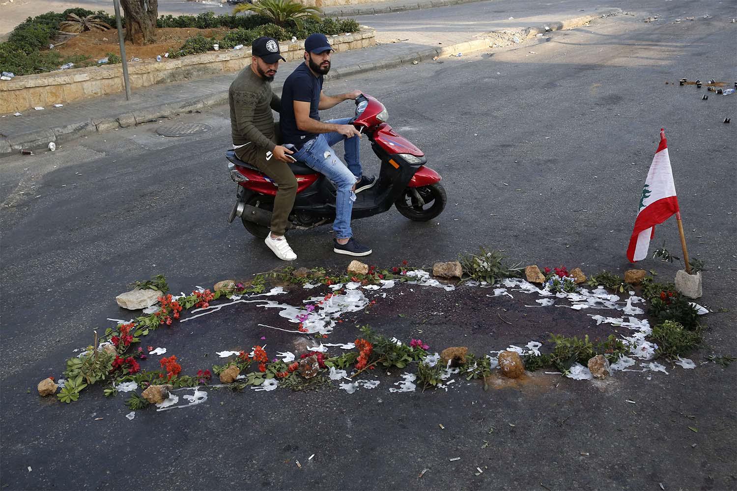 Lebanese people pass by the scene where a local official for a Lebanese political party was shot dead by a Lebanese soldier, in Khaldeh