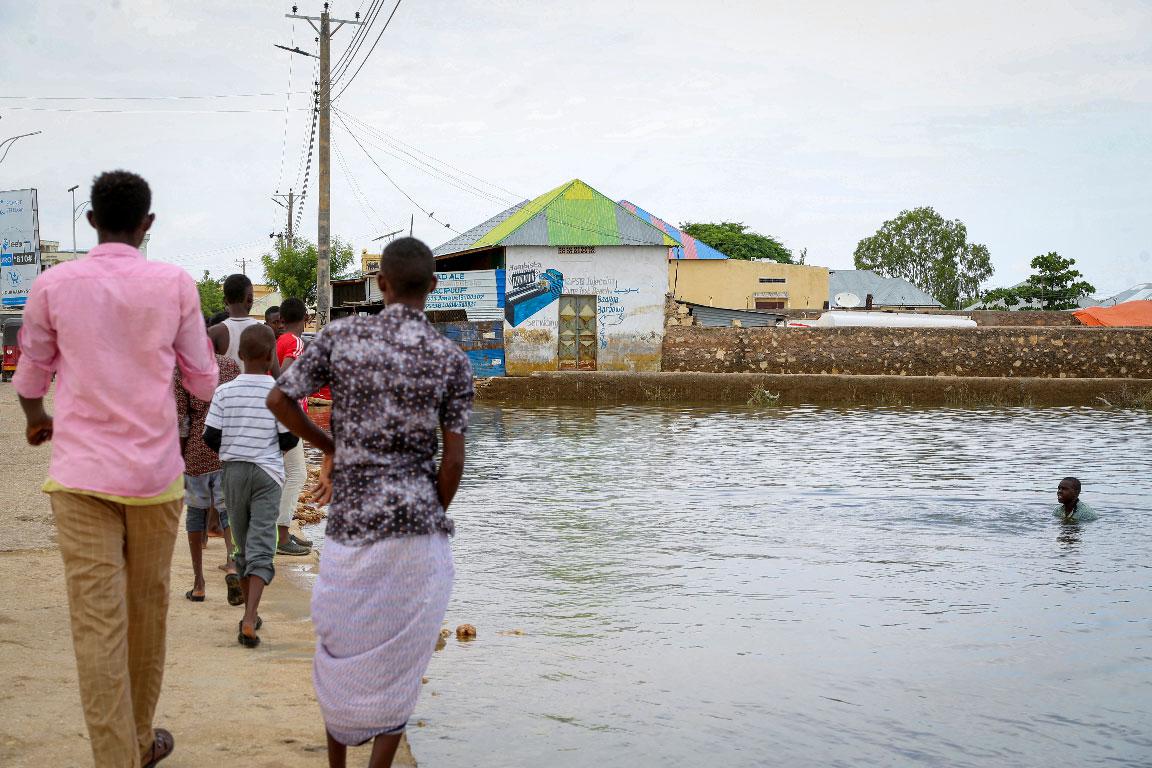 In this photo taken Monday, Nov. 4, 2019, a child swims in the floodwaters as others walk past, in the town of Beledweyne, in central Somalia