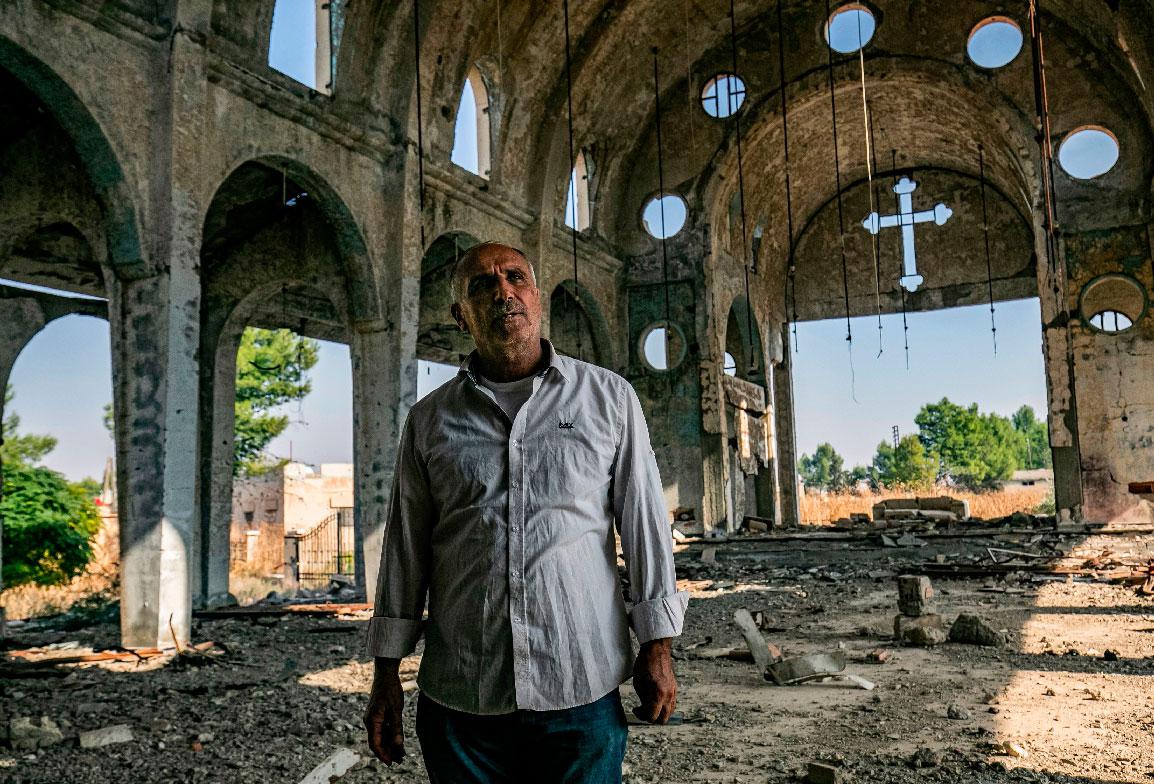 Sarkoun Selio walks in the ruins of the Assyrian Church of the Virgin Mary in the village of Tal Nasri