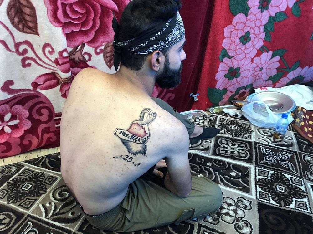 وشم الثورة يظهر على كتف أحد الشباب العراقيين