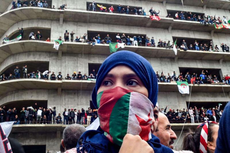  A woman covers her face with the national flag, as Algerian protesters demonstrate in the capital Algiers against ailing president's bid for a fifth term on March 8, 2019.