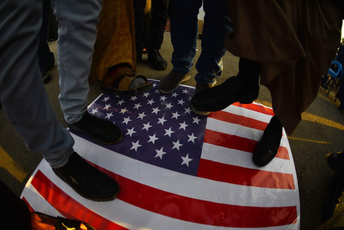 Iraqis step on a US national flag on December 30, 2019, during a demonstration to denounce the previous night's attacks
