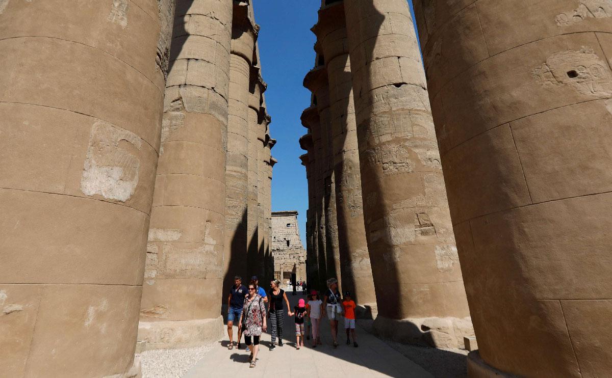 Tourists walk through columns at the site of Luxor Temple in Luxor, Egypt