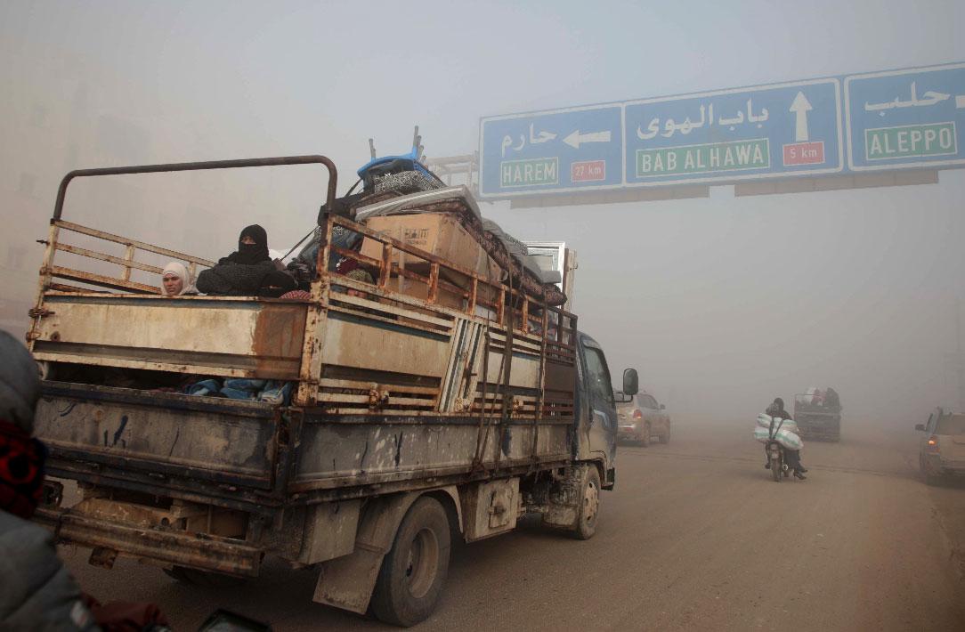 Syrians carrying their belongings drive towards the northern areas of Syria's Idlib province