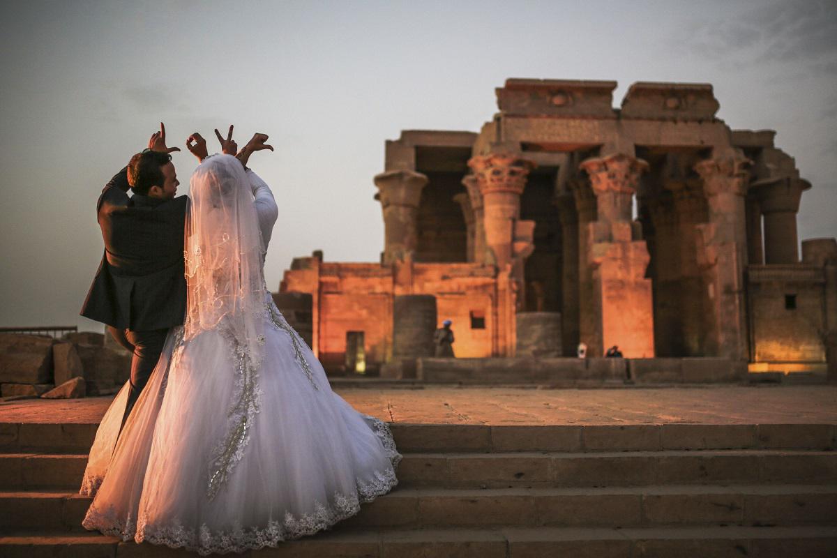 زوجان مصريان يرسمان بأصابعهما كلمة "حب" بالانكليزية أثناء زفافهما في معبد في اسوان