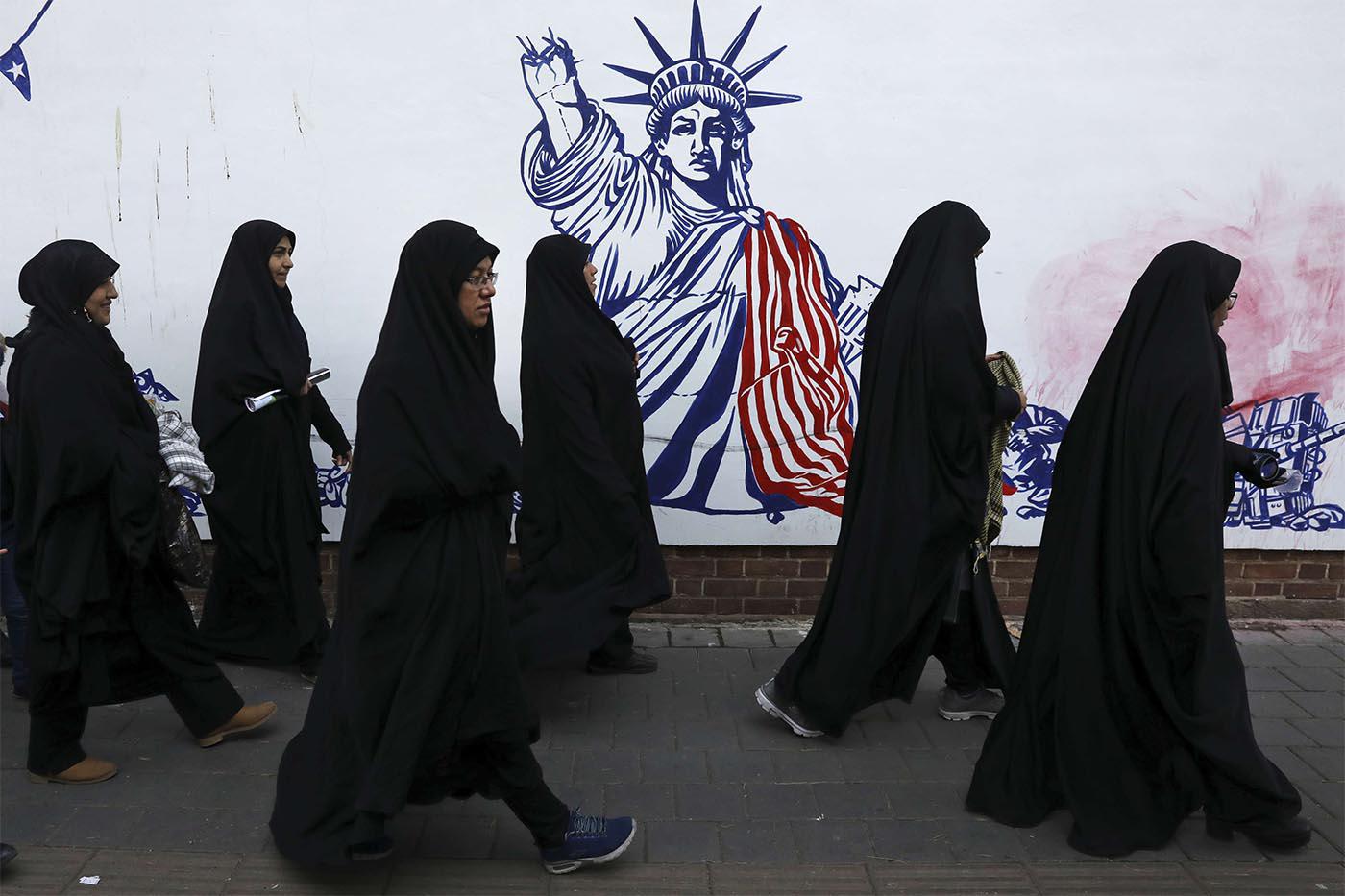 Iranian women passing a satirical drawing of the Statue of Liberty painted on the wall of the former US Embassy in Tehran