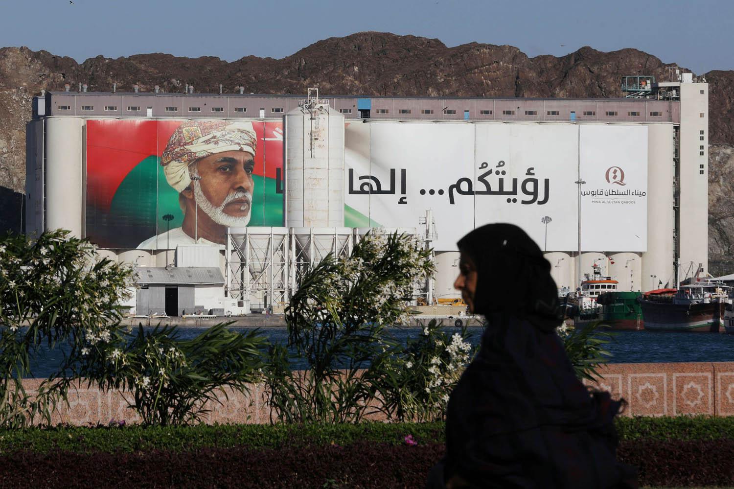 عمانية تمر بالقرب من لوحة تغطي مبنى حكومي في مسقط