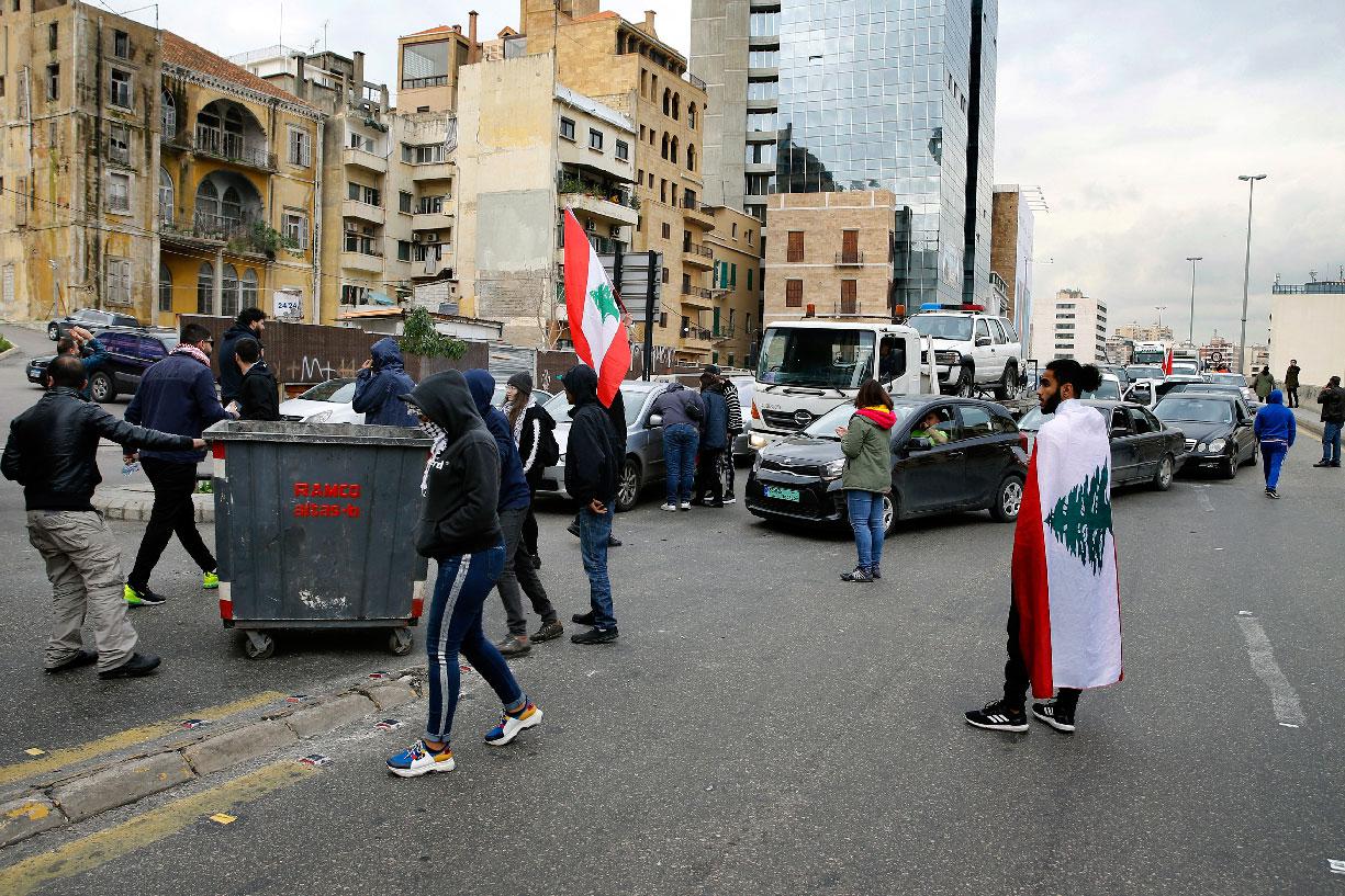Anti-government protesters block a main highway using garbage containers in Beirut
