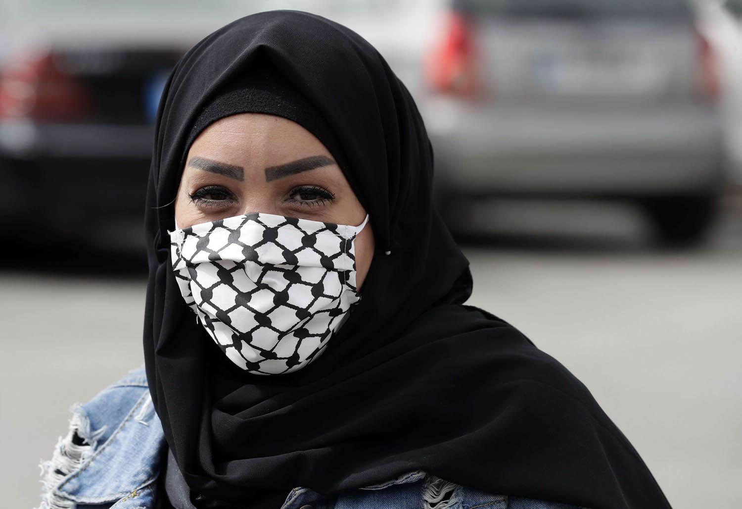 فلسطينية من مخيم برج البراجنة في بيروت ترتدي كمامة على شكل كوفية فلسطينية