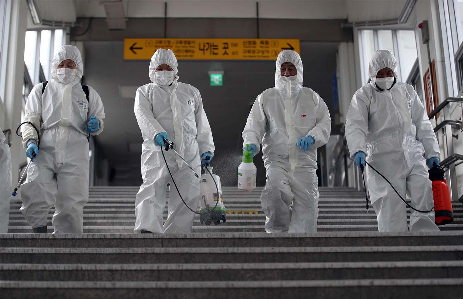 Workers wearing protective gear spray disinfectant to help prevent the spread of the COVID-19 coronavirus, at a subway station in Seoul 