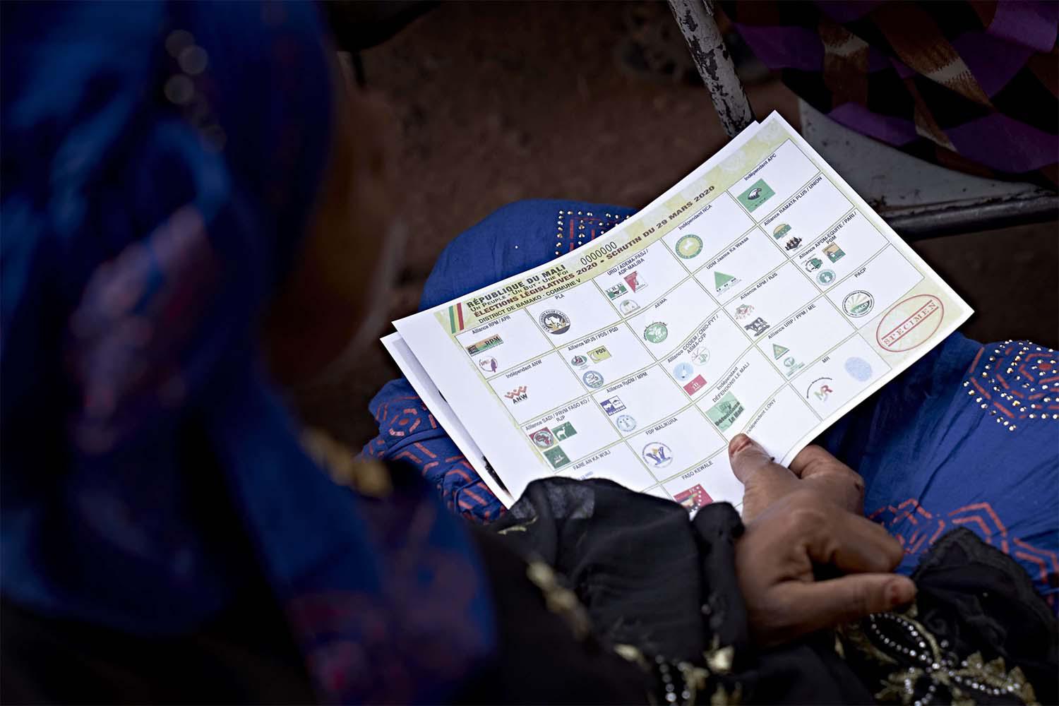 A Malian woman holds a polling paper during a meeting for the campaign of the parliamentary elections in Bamako