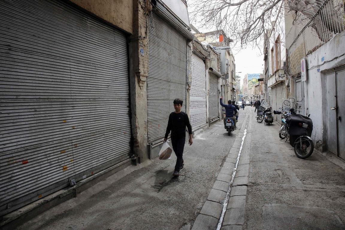 An Iranian youth walks past closed shops in Tehran's grand bazaar