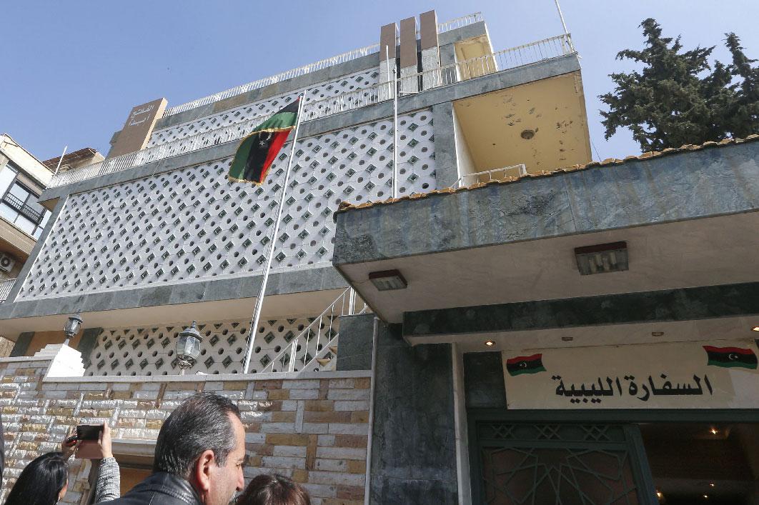 Reporters gather in front of the Libyan Embassy on the day of its reopening in Damascus