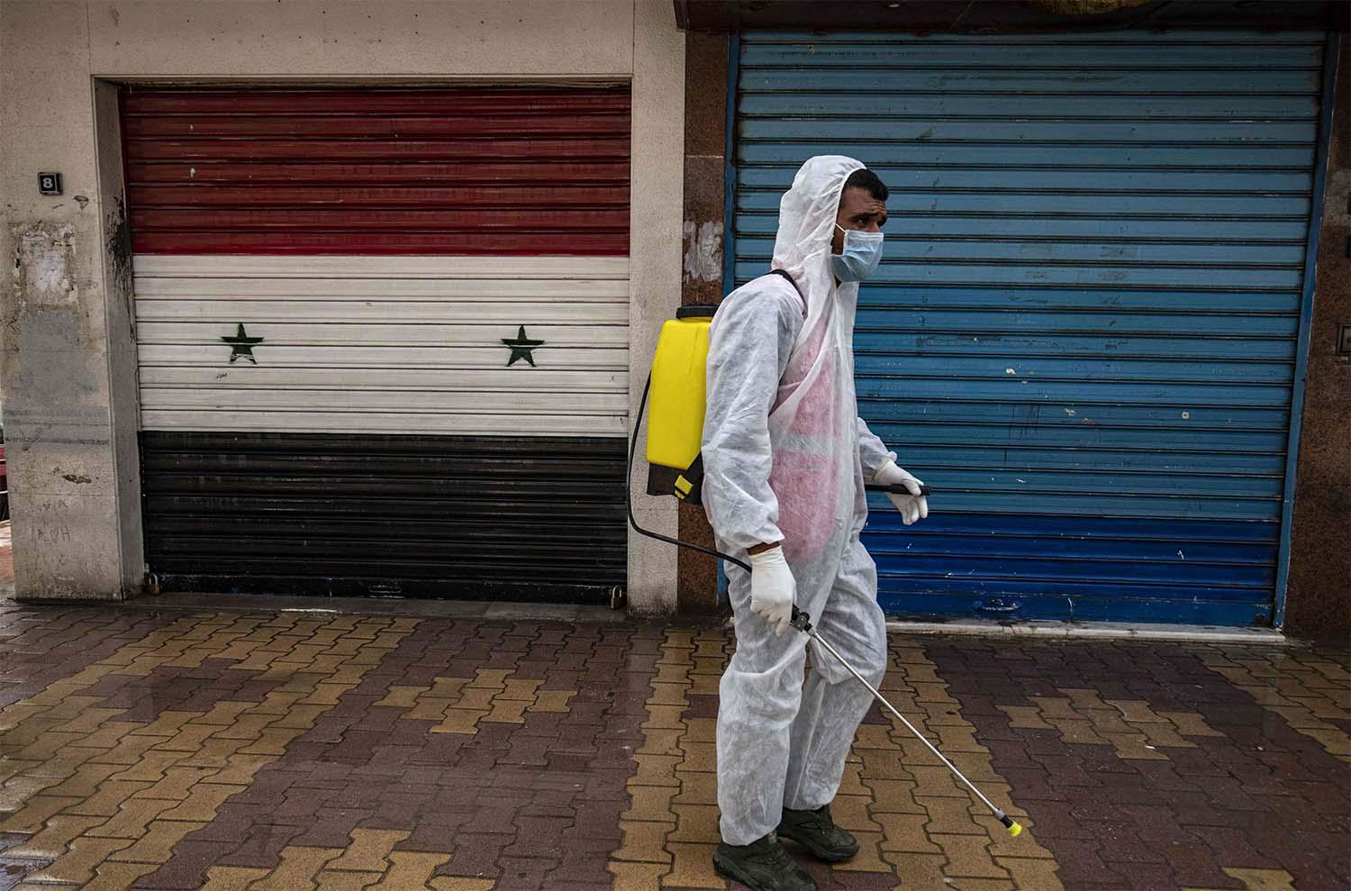 A member of disinfection units of the semi-autonomous Syrian Kurdish administration works on a street in the Kurdish-majority city of Qamishli in Syria
