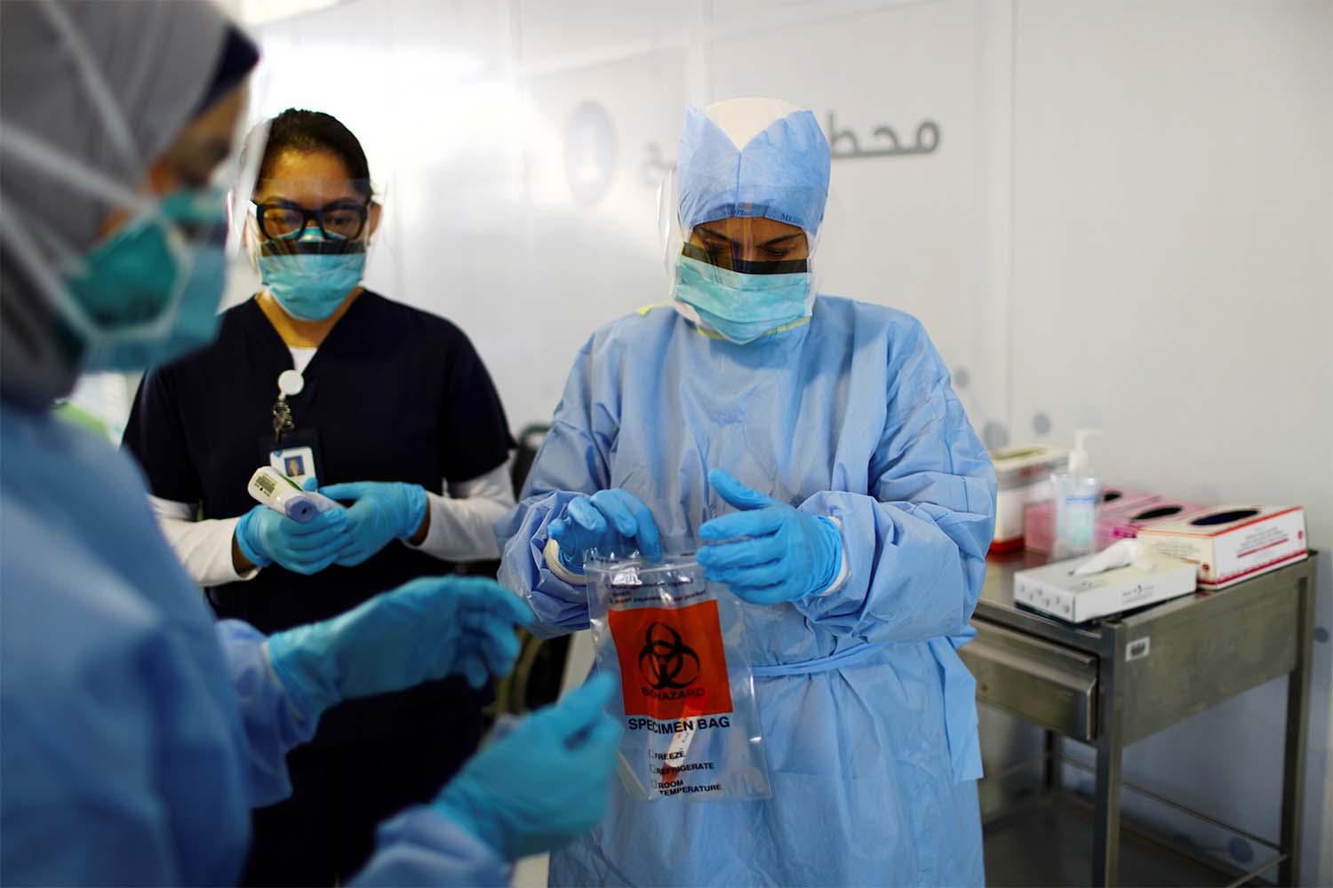 A member of medical staff wearing a protective face mask and gloves carries a swab tested during drive-thru coronavirus disease testing (COVID-19) at a screening centre in Abu Dhabi