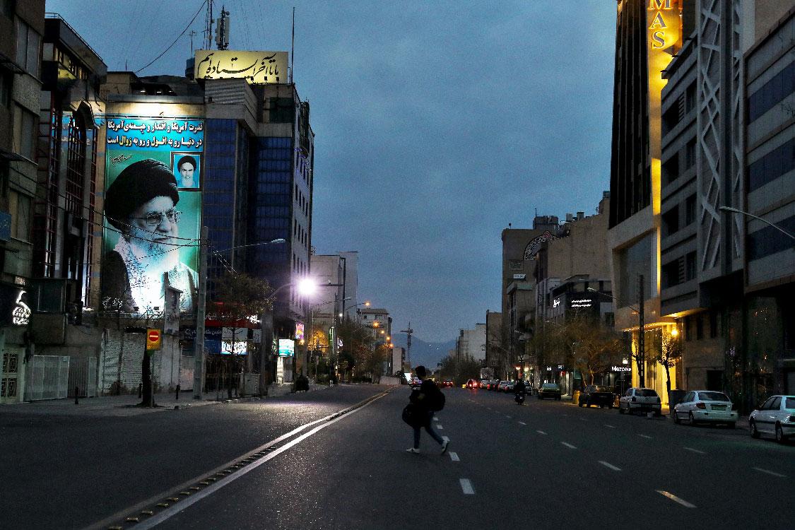 A pedestrian crosses an empty street in Tehran