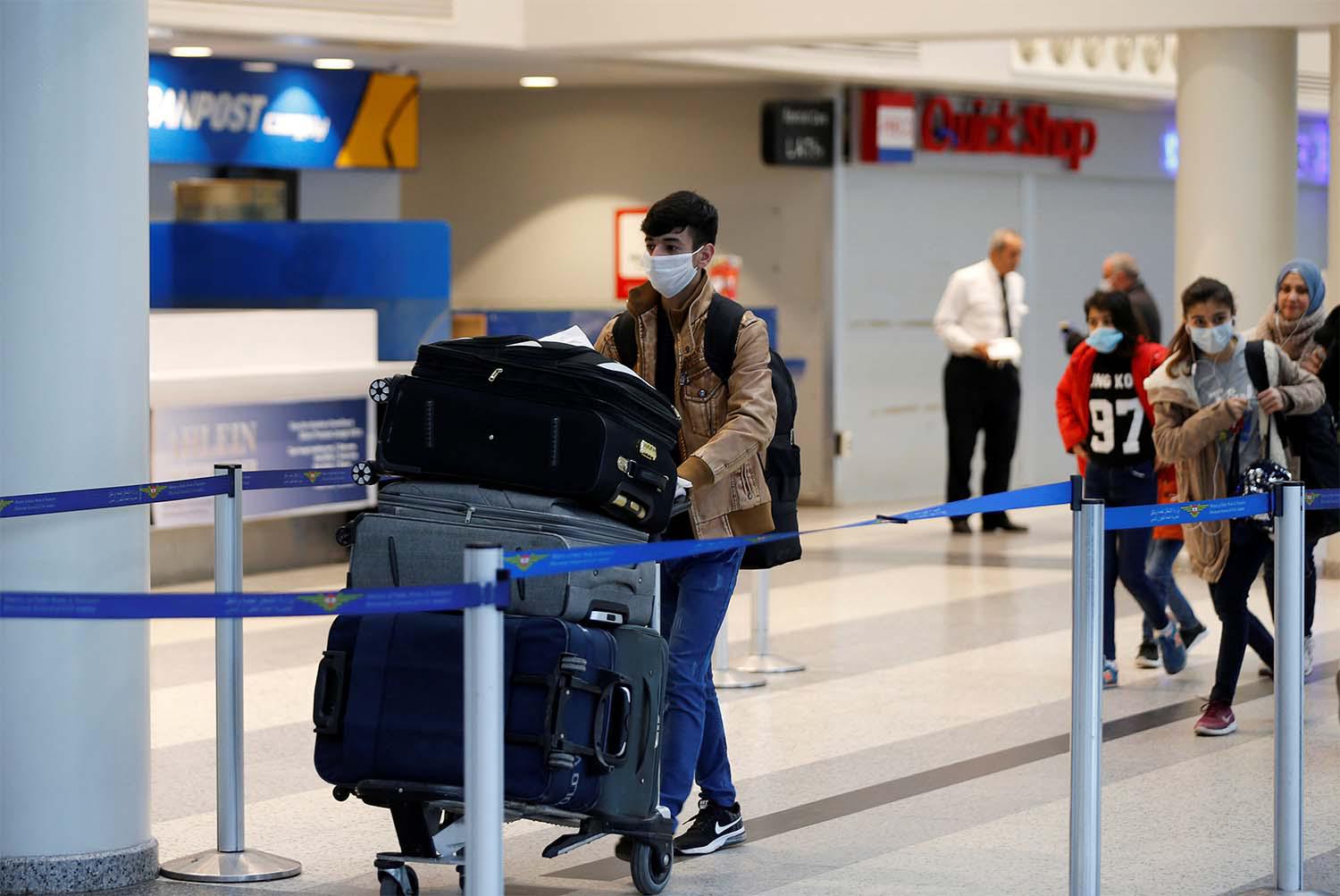 A passenger wearing a protective mask pushes a trolley at Beirut's international airport 