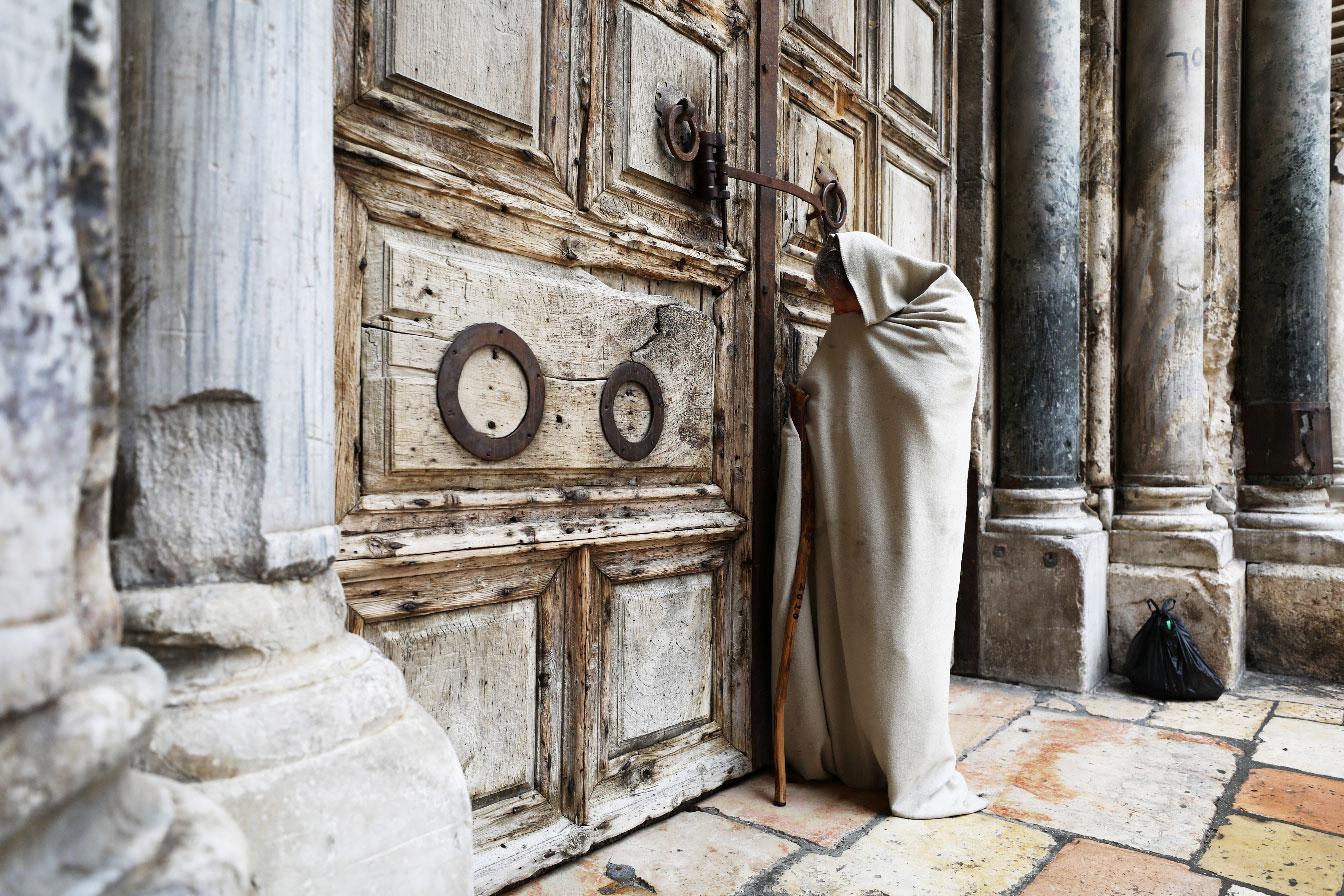A man stands in front of the closed doors of the Church of the Holy Sepulchre