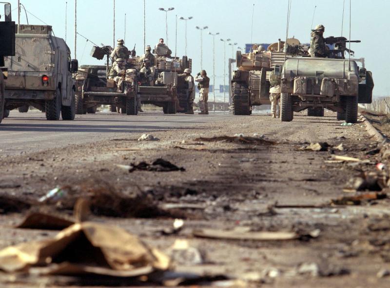 US troops block a highway in outskirts of Baghdad after a roadside bomb attack