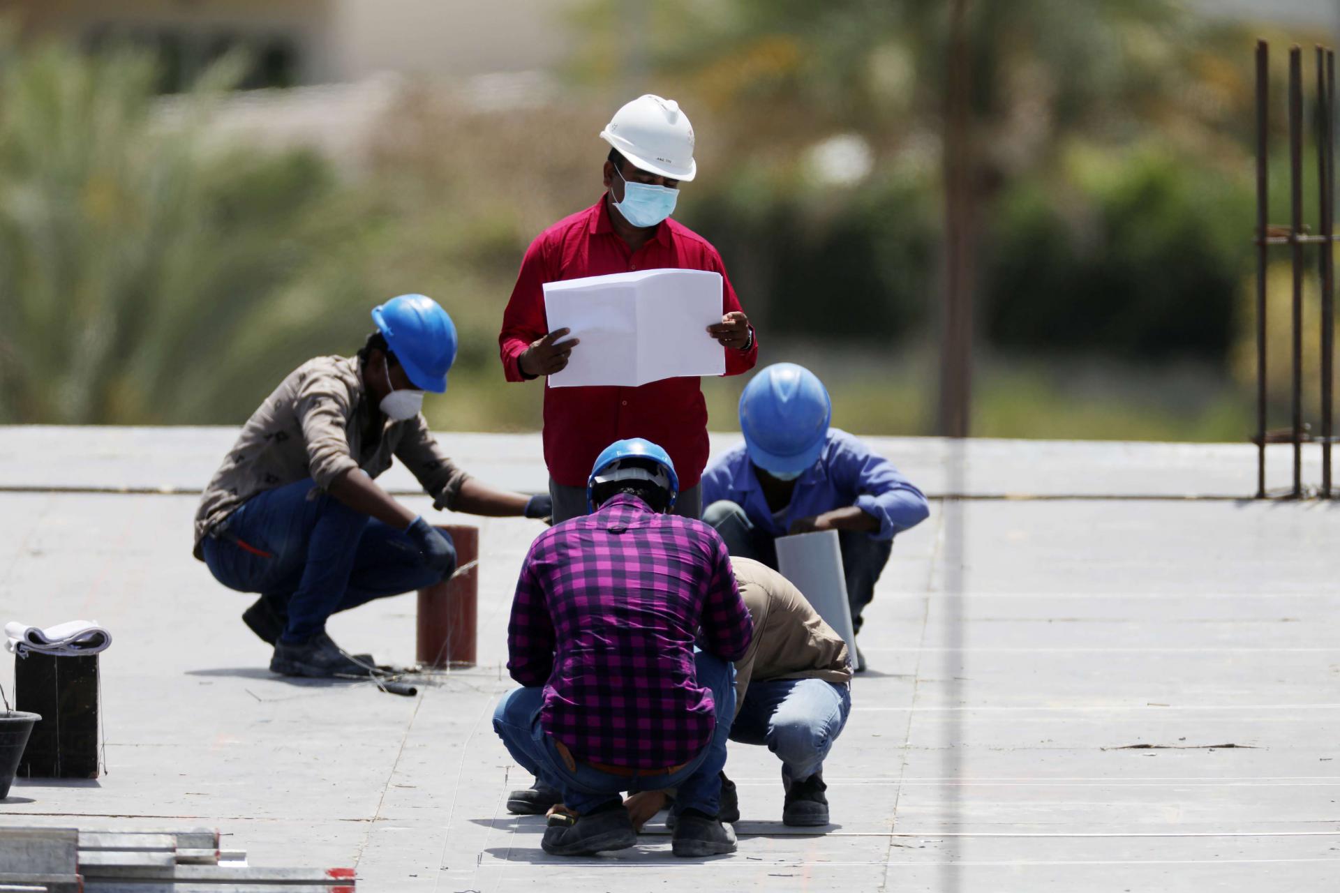 Workers wearing protective face masks work on a residential construction site in Dubai