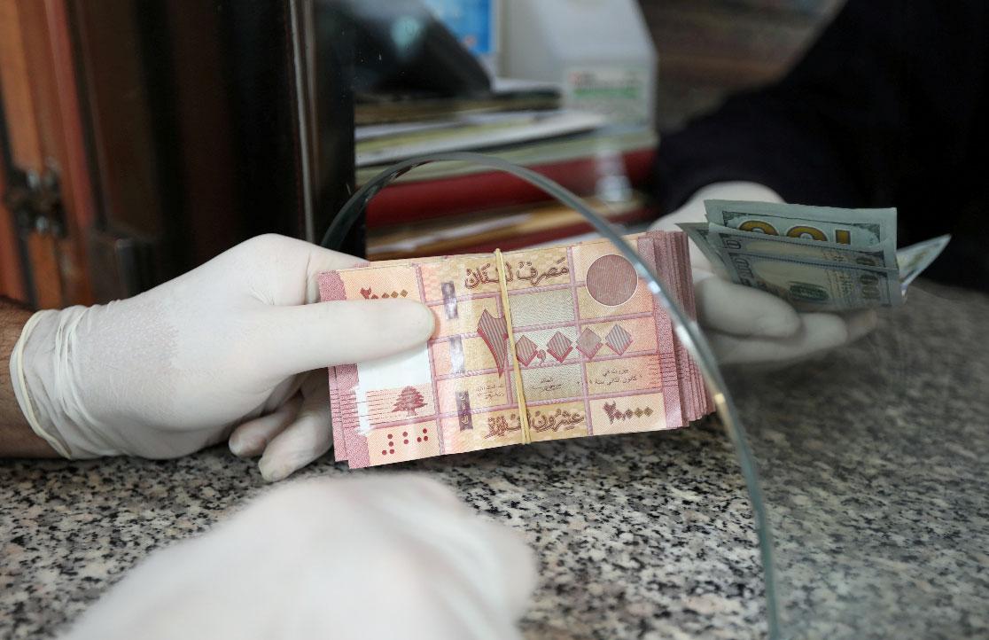 A customer wearing gloves holds Lebanese pounds at a currency exchange store