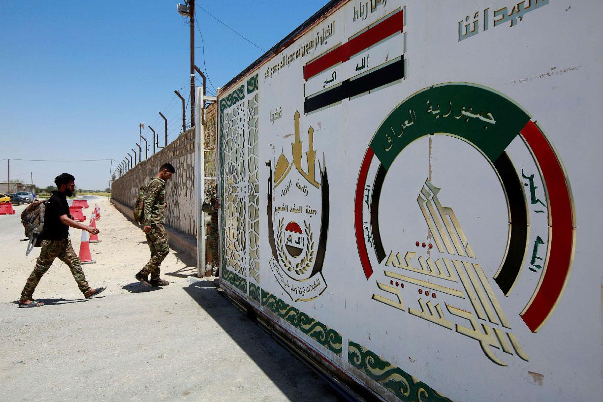 Members of Iraqi Popular Mobilization Forces (PMF) walk as they enter their headquarters in the city of Najaf
