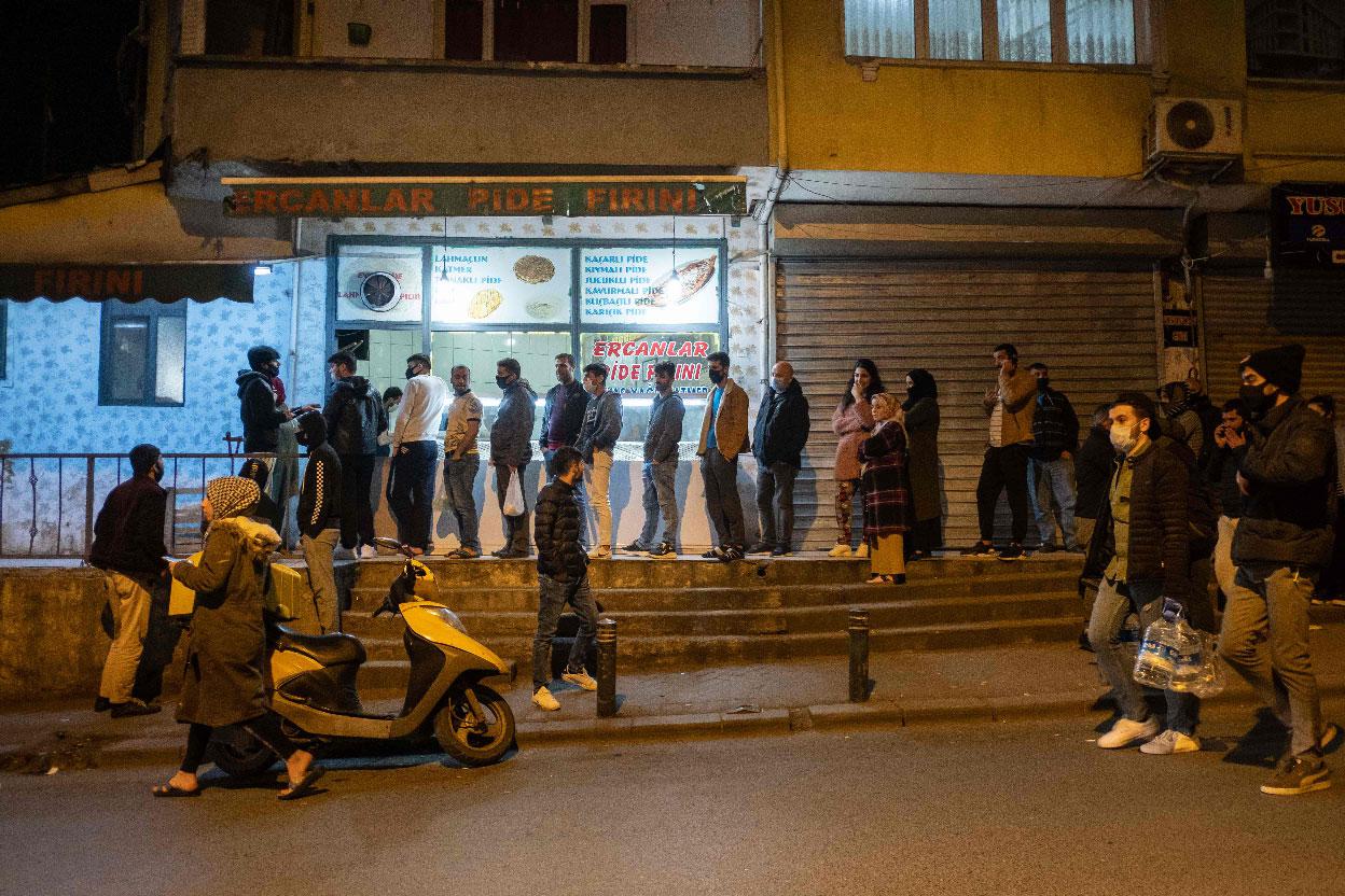 People queue at shops for food and supplies shortly before the curfew in Istanbul