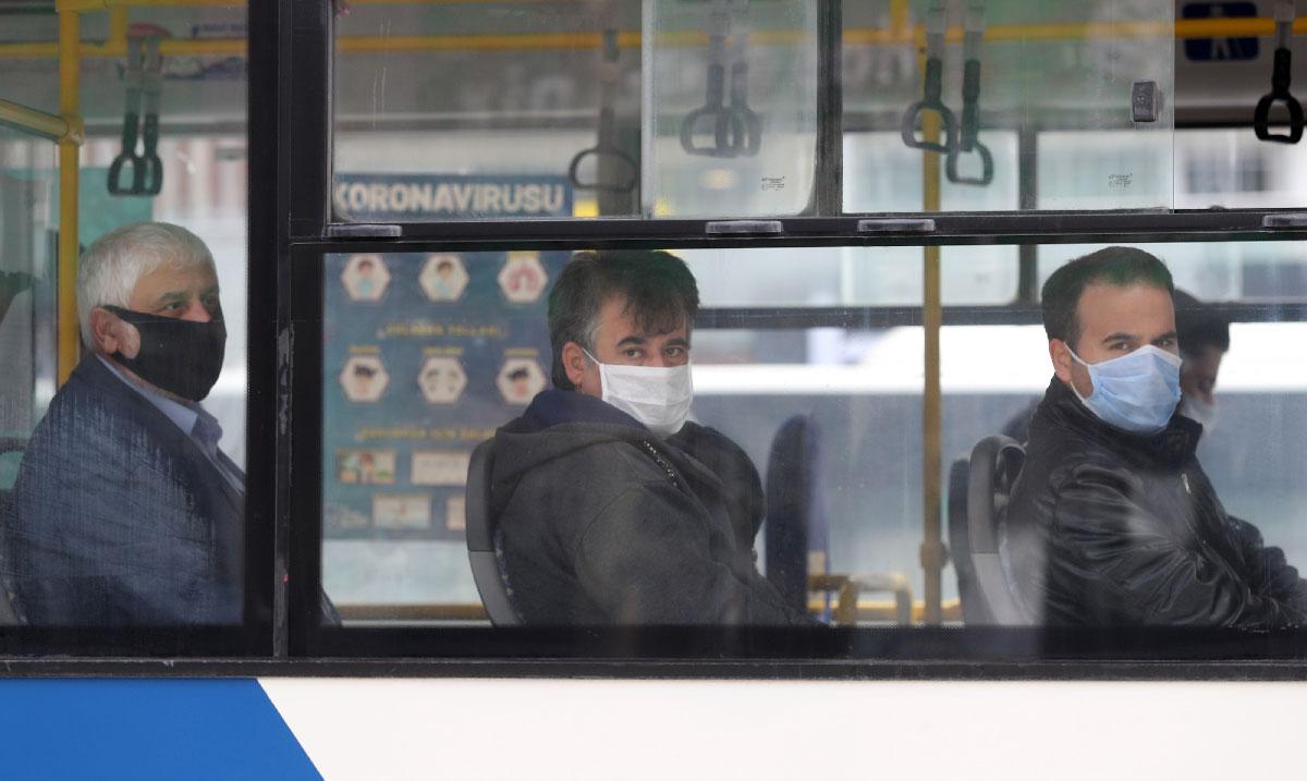 People wearing protective masks look on in a bus in Ankara