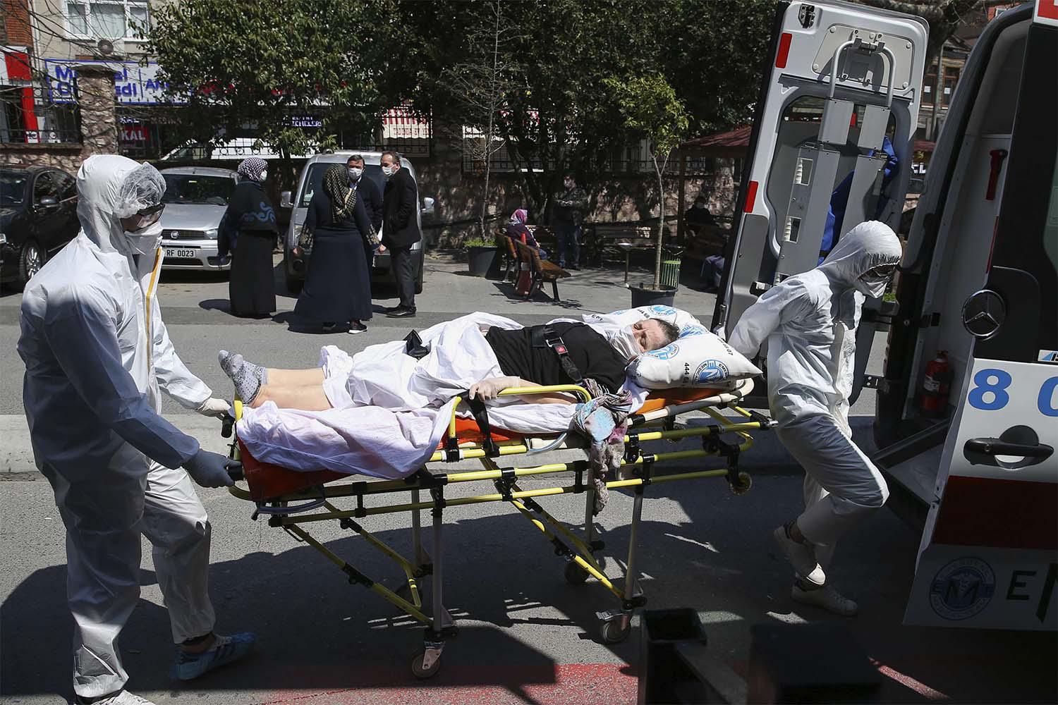 Medics wearing masks and suits against the coronavirus, take a patient out of an ambulance