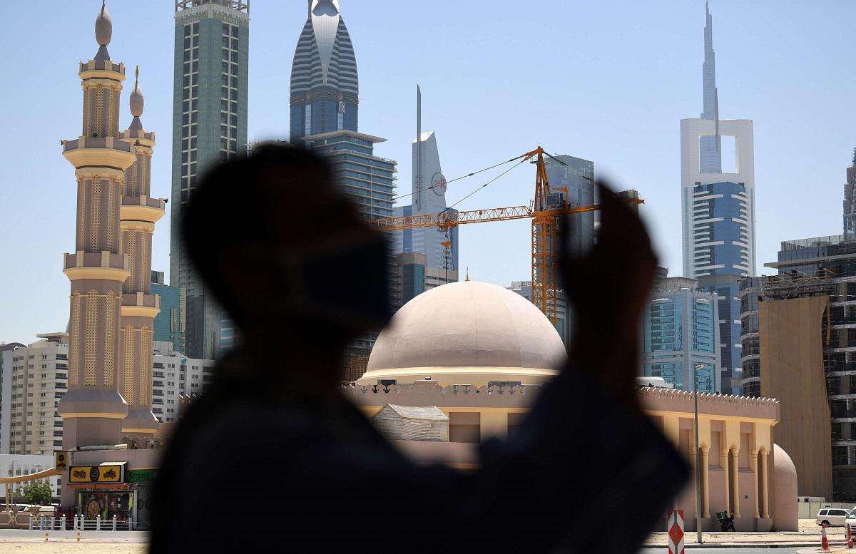 رجل يلبس كمامة يصلي بالقرب من مسجد بدبي في رمضان وسط حظر تجول بسبب كورونا