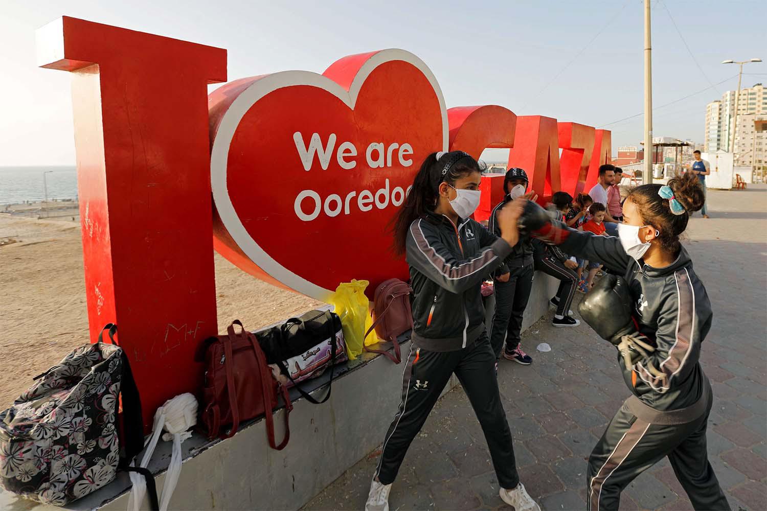 Palestinian girls participate in a boxing training session at the sidewalk of a beach 