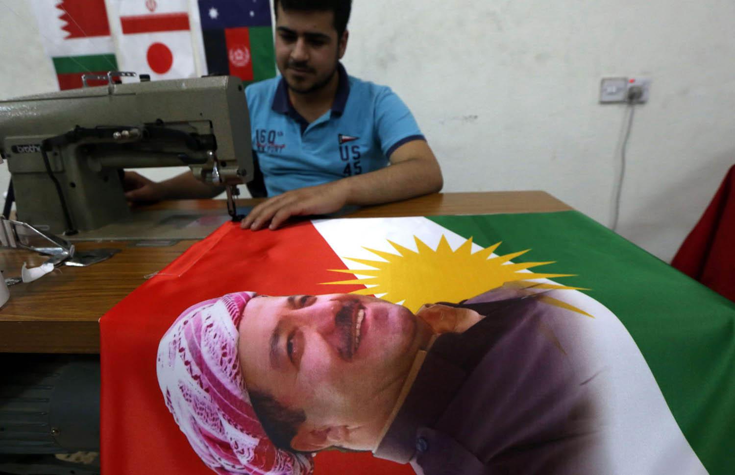خياط كردي يعد علما مع صورة مسعود بارزاني